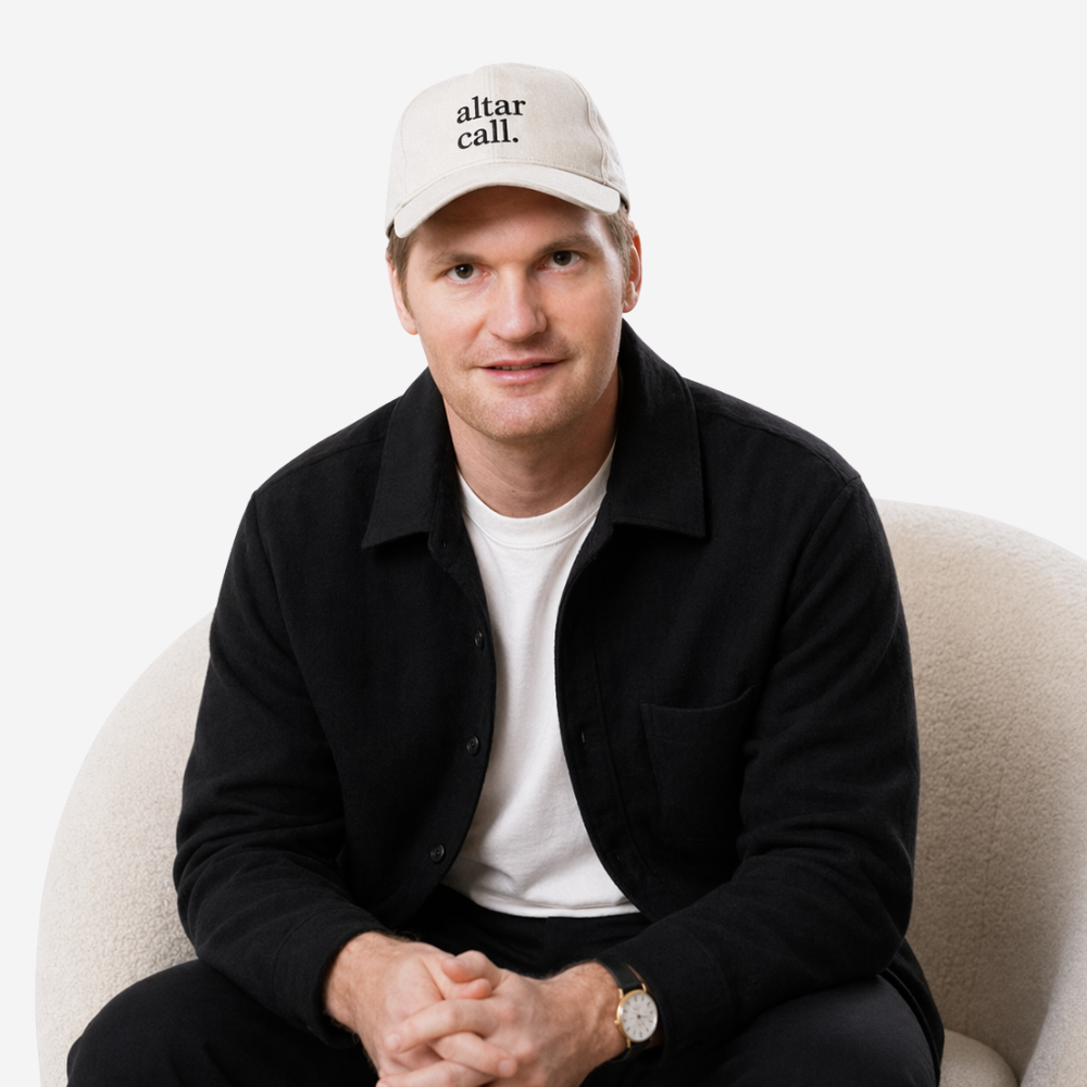 Jason Fladlien, wearing an Altar Call cap, seated in a bouclé chair.